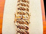 gold plated bracelet with twisted design on display on wooden stand