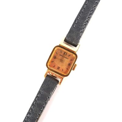 une image représentant une montre-bracelet dorée et noire dont le cadran est orné de chiffres romains