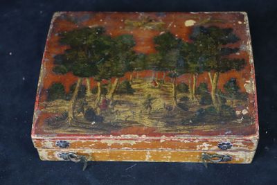 une petite boîte sur laquelle est représentée une peinture, posée sur une surface noire