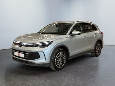 Le SUV argenté est garé dans une pièce blanche au sol noir.