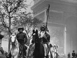 photographie en noir et blanc représentant des hommes à cheval devant l'Arc de Triomphe