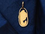 a gold pendant with a silhouette of a woman ' s face on it