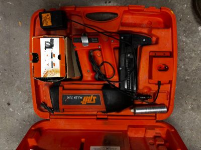 une mallette à outils orange, contenant des outils, posée par terre