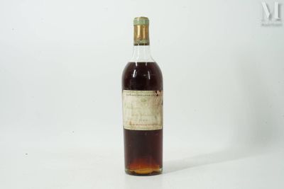 une vieille bouteille de whisky posée sur une table blanche