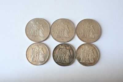 six different coins are arranged in a row on a white surface