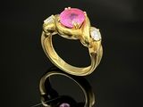 un gros plan d'une bague ornée d'une pierre rose sur un fond noir