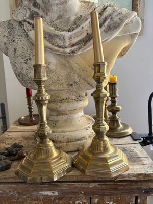two candles that are sitting on a table next to a bust
