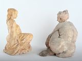 two statues sitting next to each other on a white surface