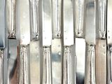 a lot of silver spoons and knives on the table