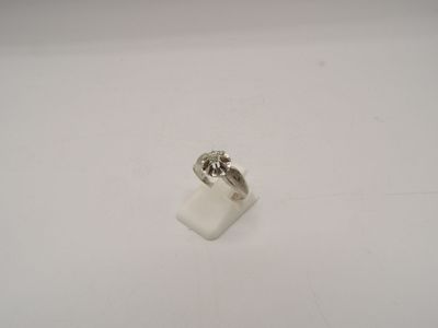 un gros plan d'une bague sertie d'un diamant, posée sur une surface blanche
