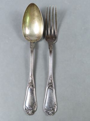 deux cuillères et une fourchette en argent sur une surface grise