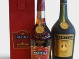 deux bouteilles de vin et une boîte rouge posées sur une surface blanche