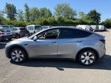 un SUV Tesla argenté garé sur un parking à côté d'autres voitures