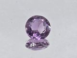 a close up of a purple gemstone on a white surface