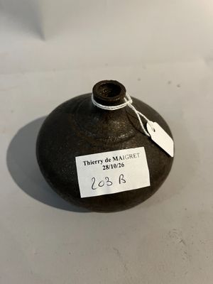 un vase noir muni d'une étiquette, posé sur une table