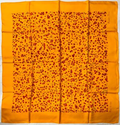 a yellow and red square scarf with small red flowers on it
