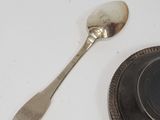 a spoon and spoon rest on a plate next to a coin