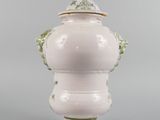 a white vase with a green lid and handles on a gray surface