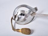 a small metal object with a spoon and a seed in it