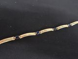 a close up of a gold bracelet with blue stones on a black surface