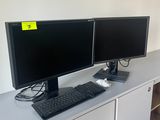 deux écrans d'ordinateur posés sur un bureau blanc