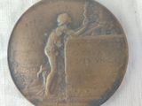 a bronze medal that has a woman holding a bird on it