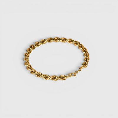 a gold bracelet with a twisted rope on a white background