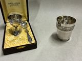 two silver cups and spoons in a box on a table