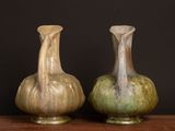 two vases sitting on a table with a black background