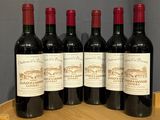 four bottles of red wine sitting on top of a wooden barrel