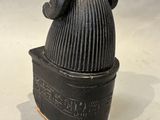 a small black pot with a hat on top of it