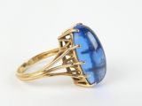 a close up of a gold ring with a blue stone