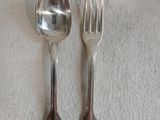 deux cuillères en argent et une fourchette posées sur une nappe blanche