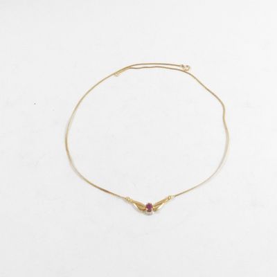 un bracelet en or orné d'une pierre rouge sur fond blanc
