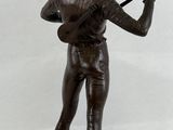 bronze statue of a man with a sword and a hat on a wooden base