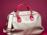 a white and red handbag sitting on top of a pink surface