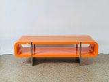 une table basse orange posée sur un sol recouvert de moquette