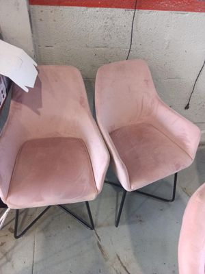 une paire de fauteuils en velours rose aux pieds en métal noir dans une pièce