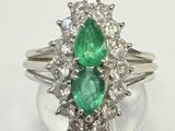 un gros plan d'une bague sertie de deux émeraudes et de diamants