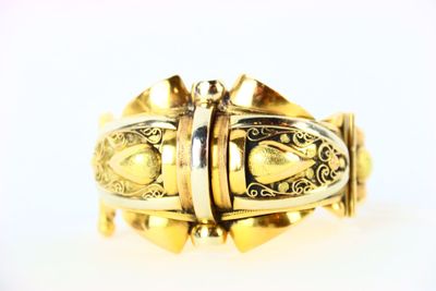 une image d'un gros plan d'un bracelet en or sur une surface blanche