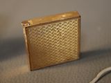 a gold lighter sitting on a table with a cord