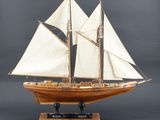 maquette en bois d'un voilier aux voiles blanches, posée sur un socle
