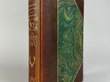 an old book with a green cover sitting on a white surface