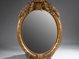 an ornately carved mirror with a gold frame on a white surface