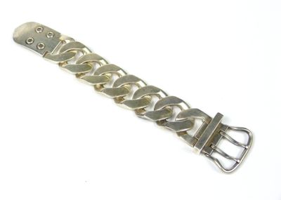 une image montrant un gros plan d'un bracelet en métal posé sur une surface blanche