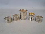 several silver cups and spoons sitting on a white surface