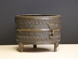 a small bronze pot on a stand on a table