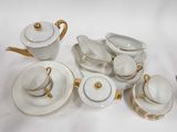 beaucoup d'assiettes et de tasses blanches et dorées sur la table