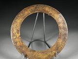 une photo d'une sculpture métallique représentant un objet circulaire posé sur un socle