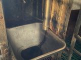 a dirty sink in a dirty room with a metal grate